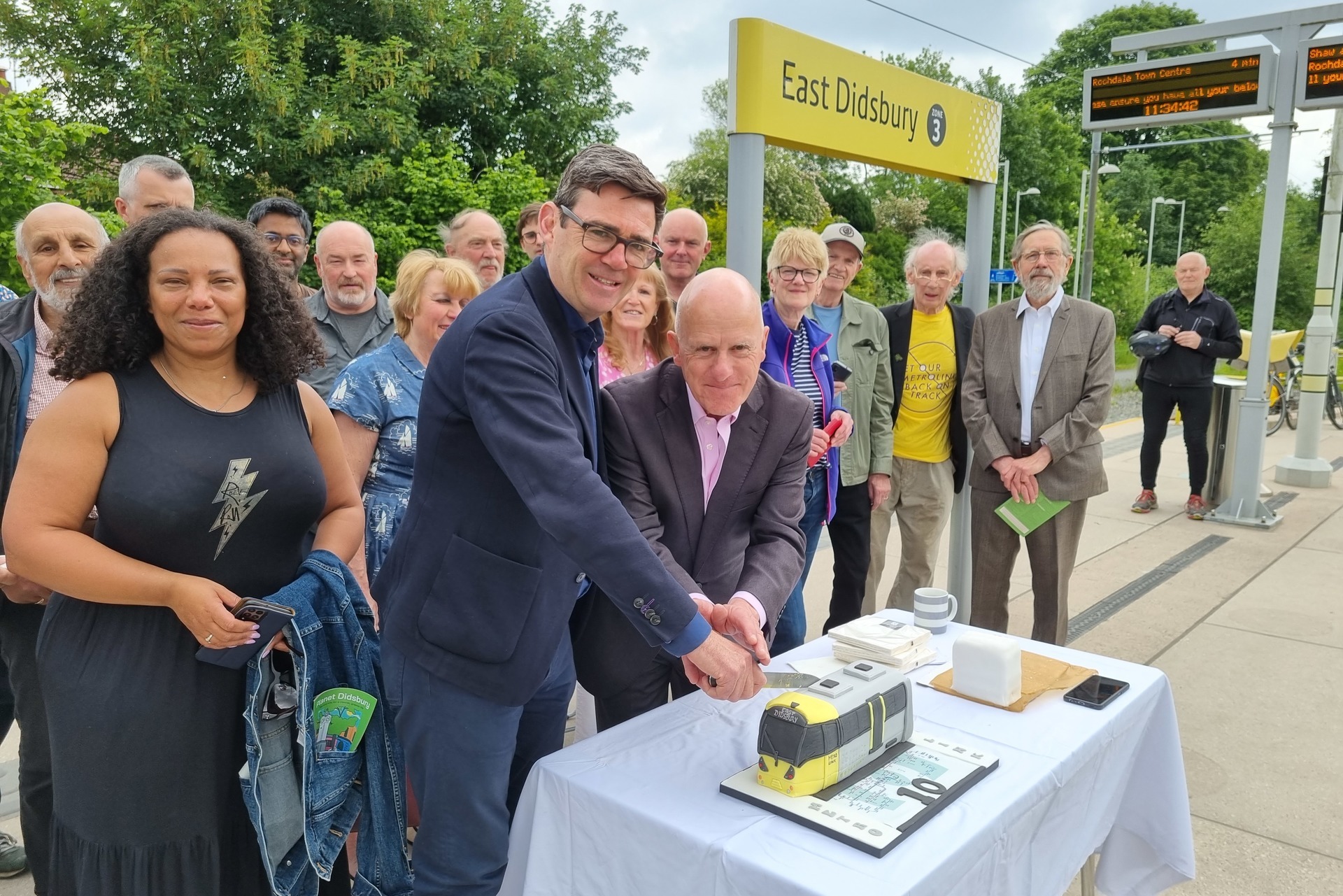 To celebrate 10 years of operation, the Mayor joined local Councillor Andrew Simcock, former chair of the Transport for Greater Manchester Committee, Andrew Fender – who helped bring Metrolink to the city-region during his four-decade spell in local politics – and ex-Didsbury councillor Geoff Bridson at the tram stop, where they handed slices of a Metrolink cake to passengers.