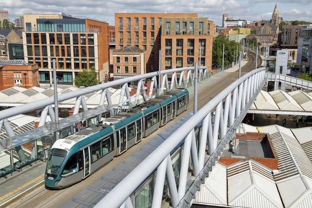 A Nottingham Alstom tram crosses the bridge over the railway station. (NET)